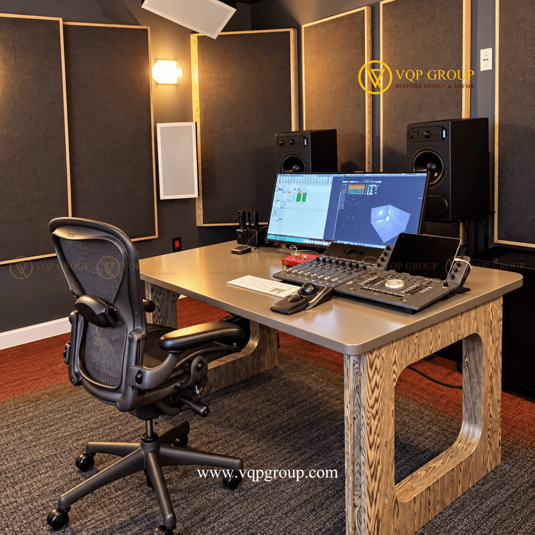 Bàn điều khiển âm thanh và thiết bị sản xuất âm nhạc tại AMBER STUDIO Mô tả ảnh: Góc nhìn chéo khu vực bàn làm việc với màn hình hiển thị phần mềm âm thanh, bàn điều khiển, loa kiểm âm và ghế công thái học.