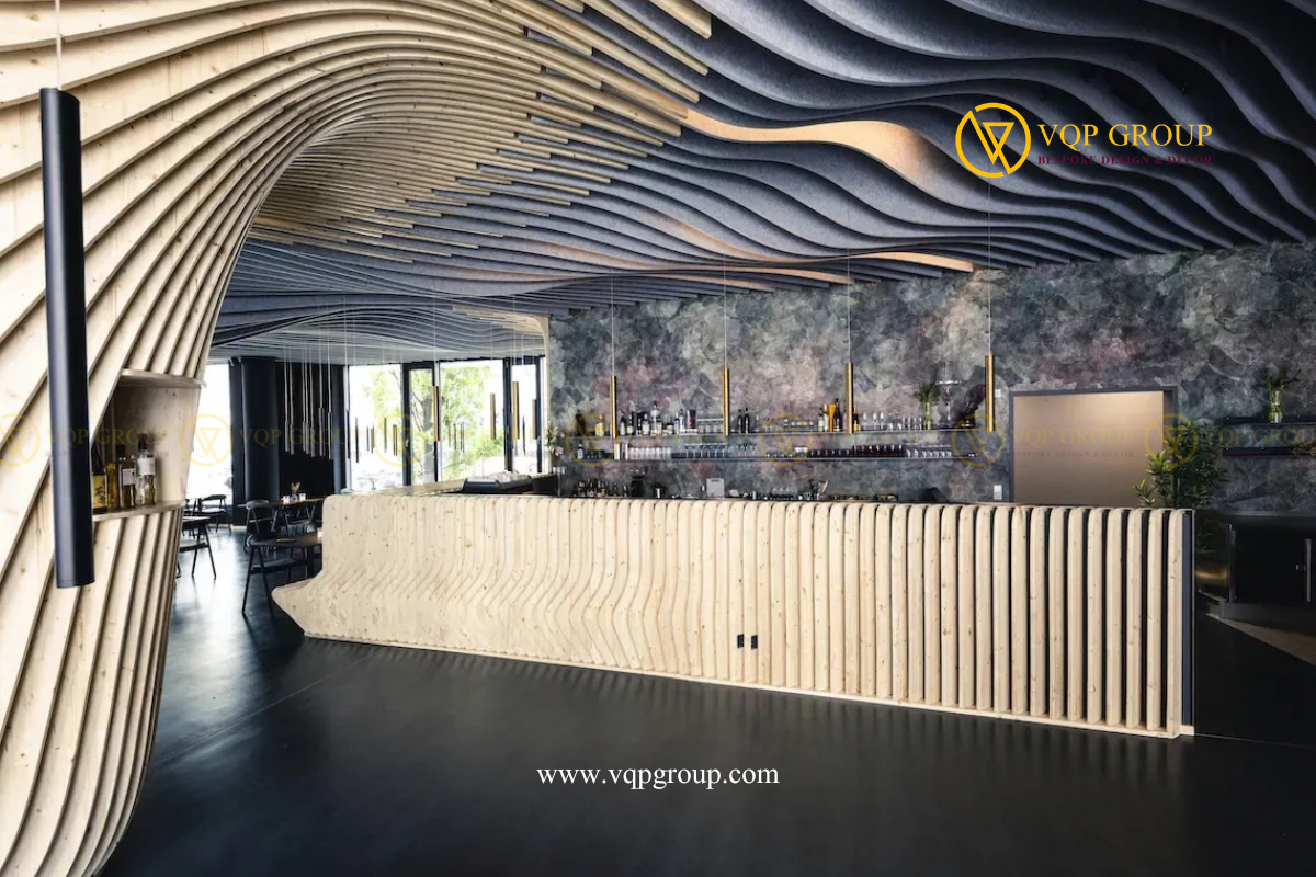 Hệ lam trần uốn lượn màu xám kết hợp các đường gỗ sáng phía trên quầy bar nhà hàng